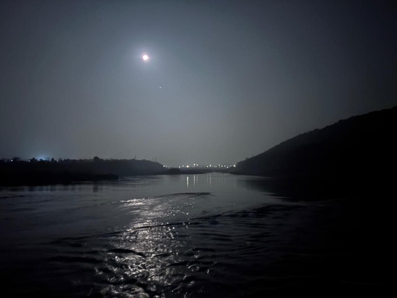 Moonlight reflected on a river between dark hills at night