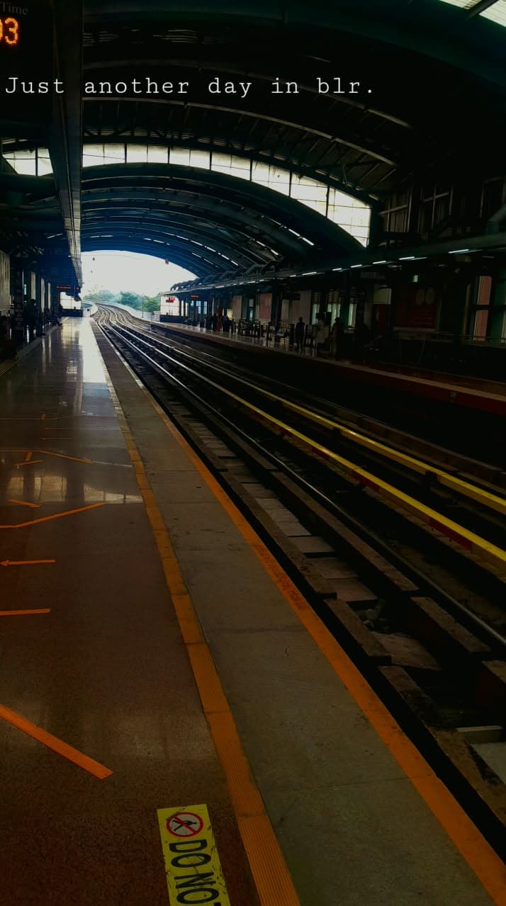 An empty metro station platform and railway tracks beneath a curved roof